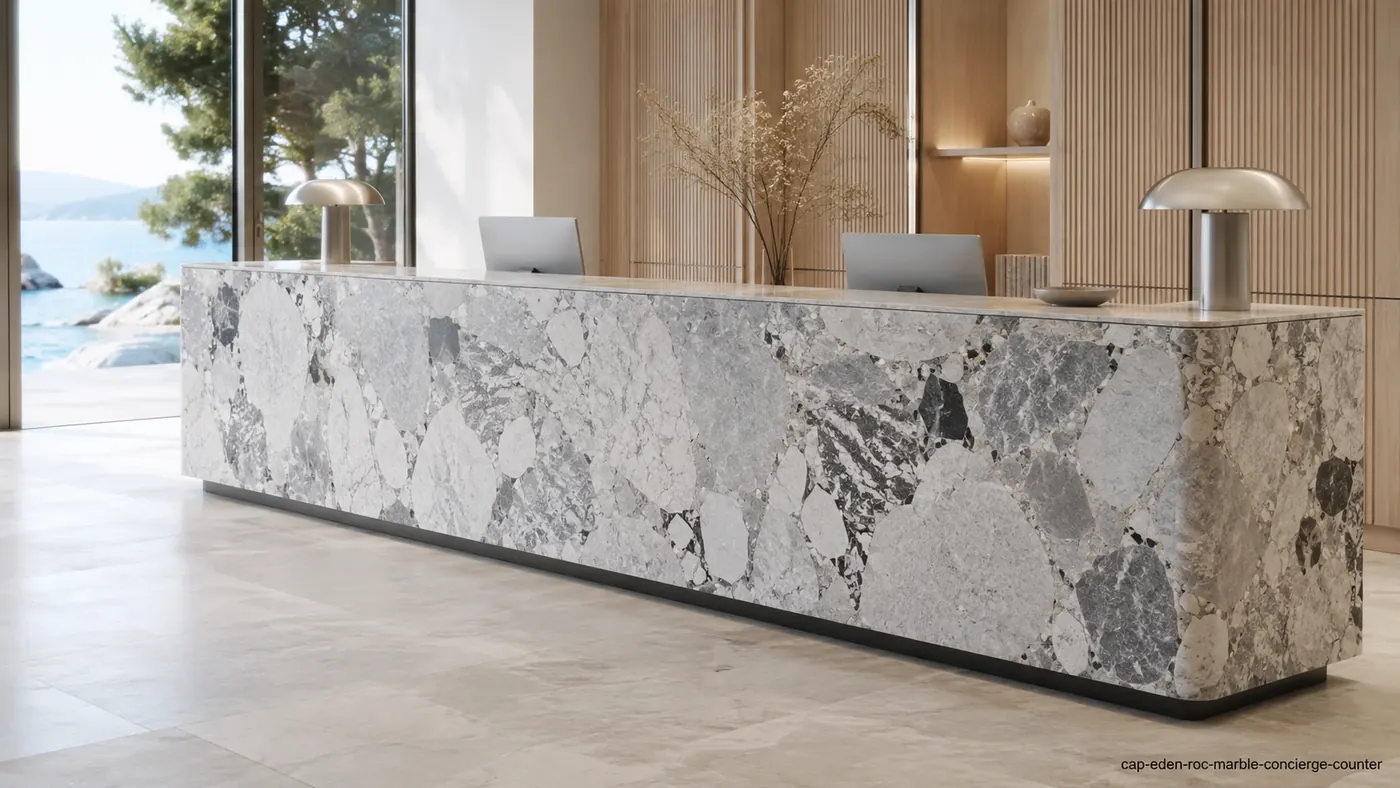 Cap Eden Roc Marble concierge counter with silver-grey breccia, white fragments and dark angular inclusions.