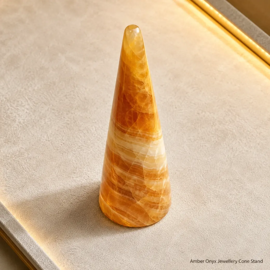 Amber onyx ring cone on cream suede, overhead diagonal view revealing translucent bands and polished contours.