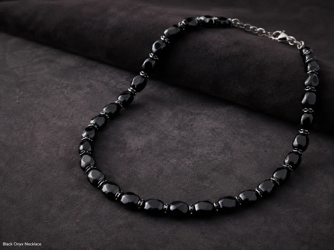 Polished black onyx necklace with glossy chalcedony elements arranged on dark premium fabric