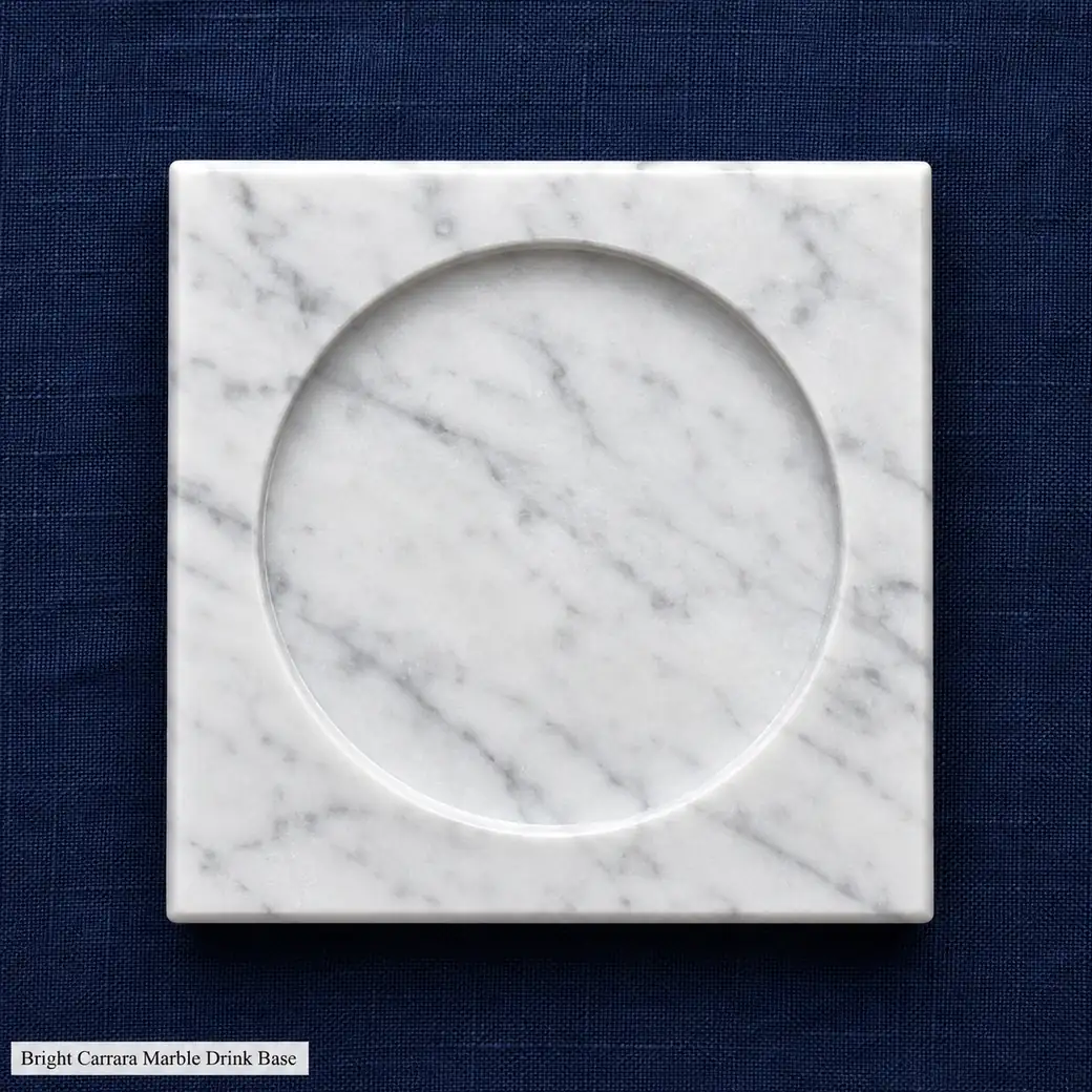Overhead Carrara glass coaster on navy linen with polished fine veining and shallow circular recess.