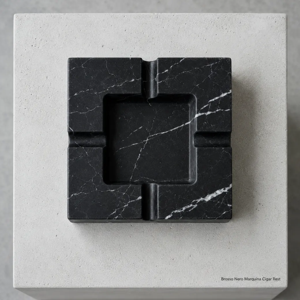 Nero Marquina smoking tray on raw concrete, overhead view showing four rests, central recess and white veining.