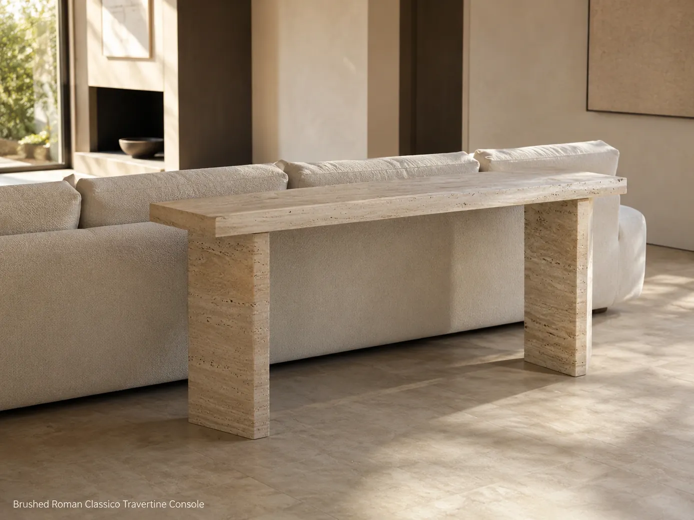 Brushed Roman travertine console positioned behind a low sofa and photographed from across the room