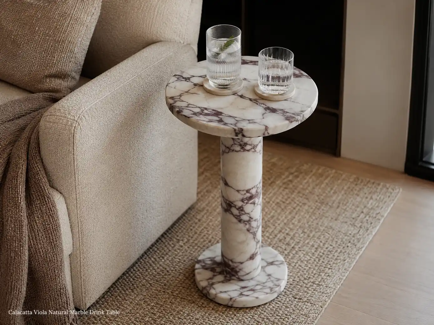 Honed Calacatta Viola drink table beside lounge seating with deep plum veining and drinks on coasters