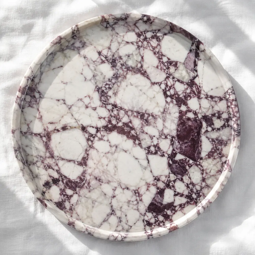 Overhead Calacatta Viola dessert platter on white linen with deep violet veins and mirror-gloss finish.