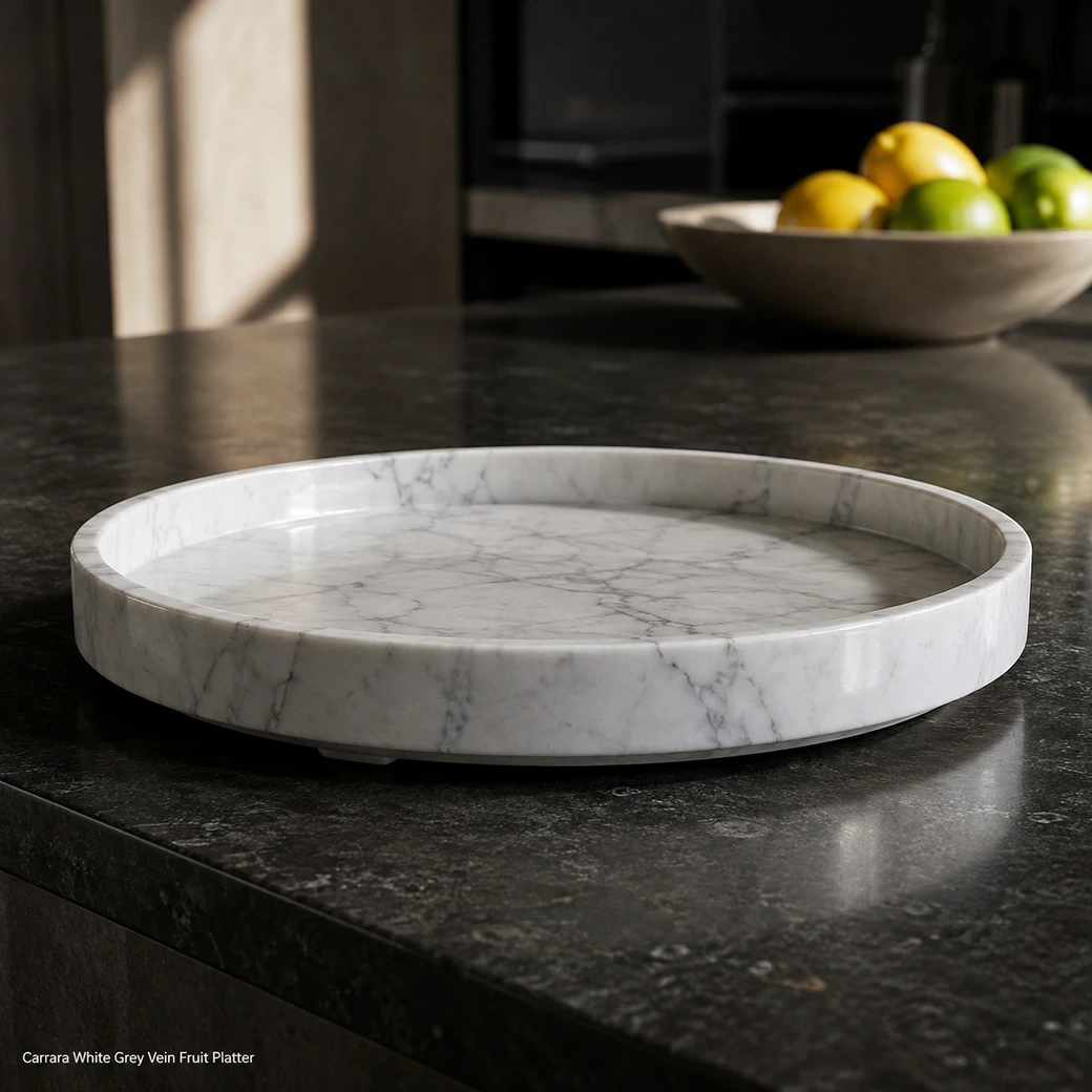 Low-edge Carrara White fruit platter on dark stone with visible raised rim and fine grey natural movement.