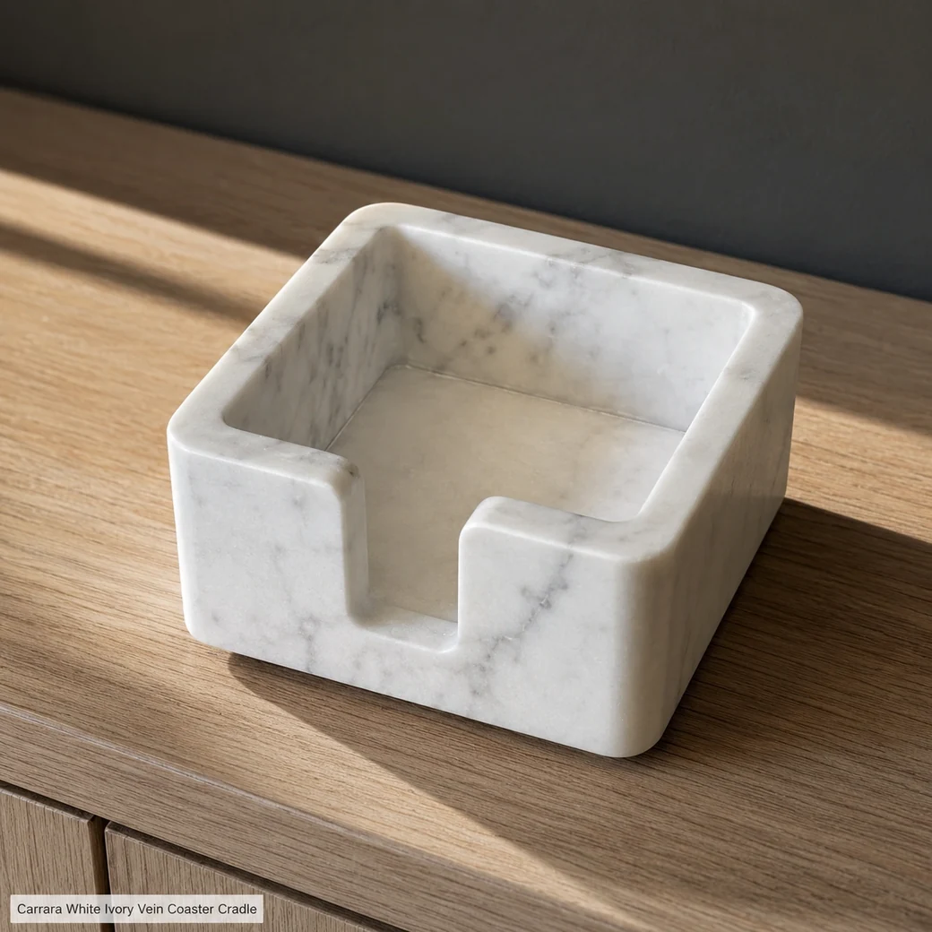 High rear view of ivory Carrara coaster caddy on pale oak, exposing the recessed cavity, thick rim and soft grey veins.