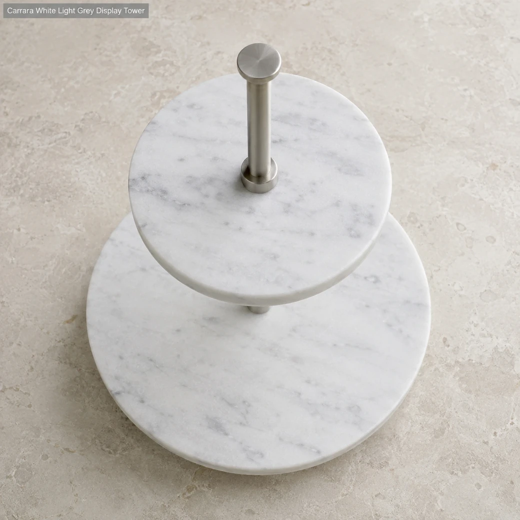 Top view of honed Carrara two-level stand on pale stone, showing concentric tiers, light grey veins and central metal pole.