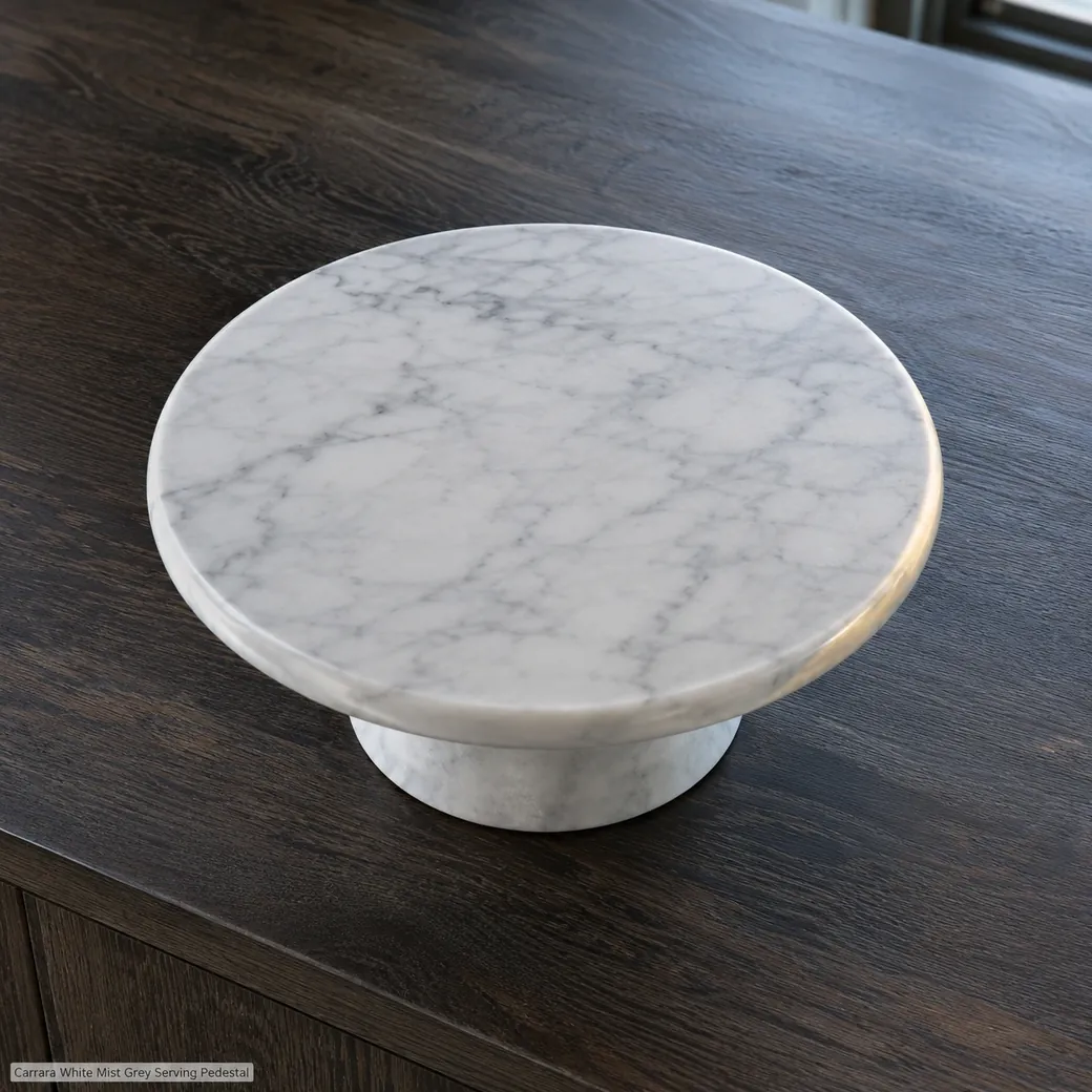 High rear view of Carrara serving pedestal on dark oak, revealing the full veined top, polished rim and low stone base.