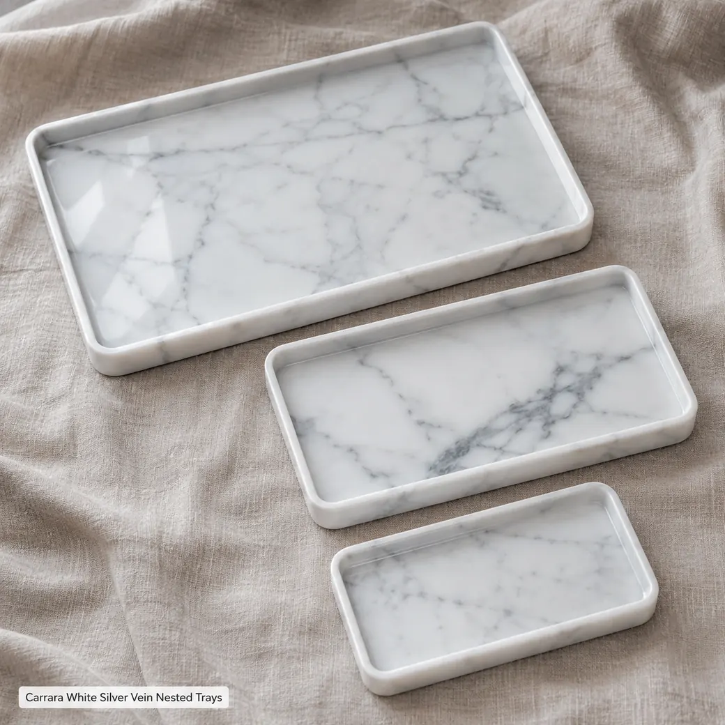 Top-down Carrara White serving trays fanned on taupe linen with pearl grey veining and soft polish.