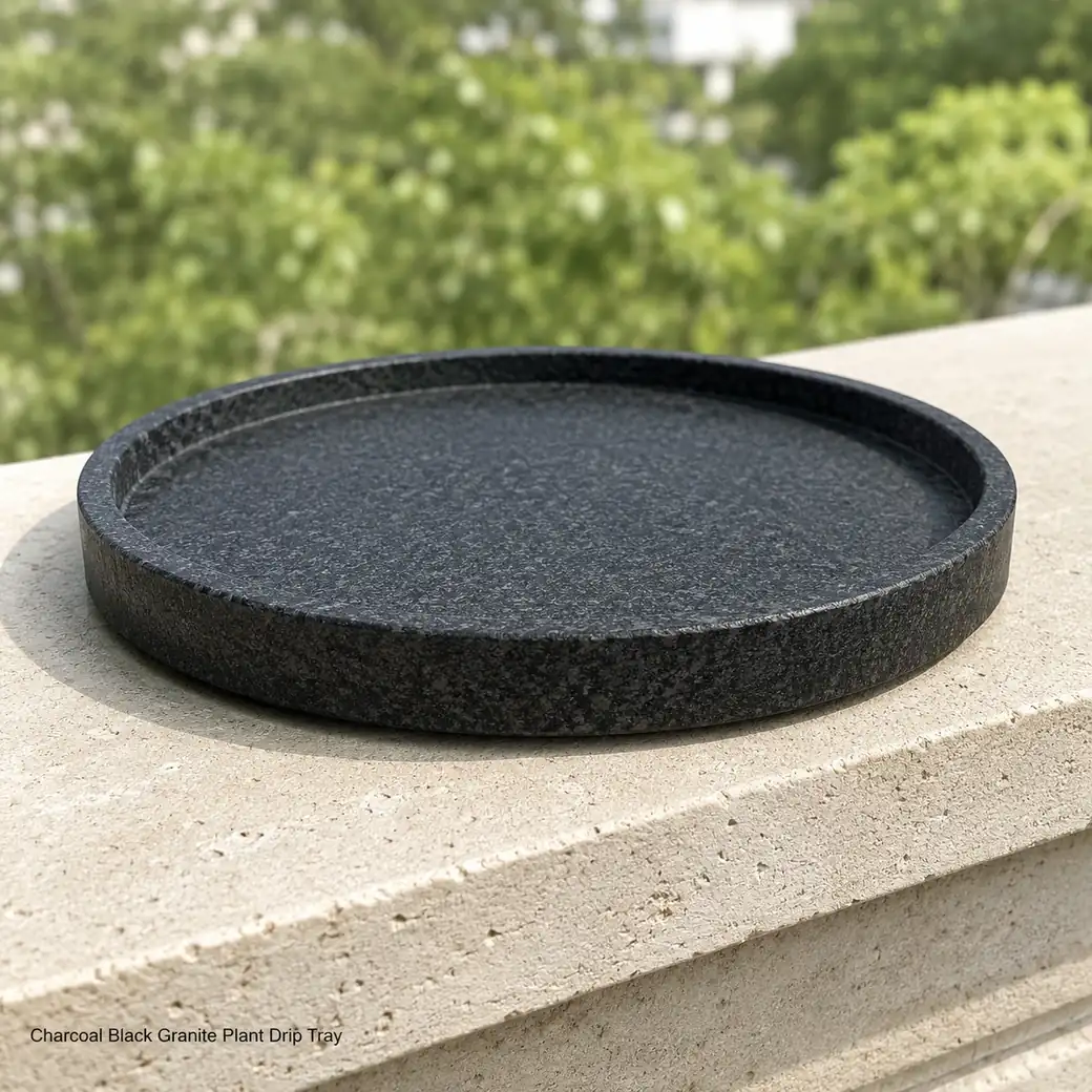 Charcoal granite plant drip tray on pale balcony ledge, low profile view showing leathered grain and raised rim.