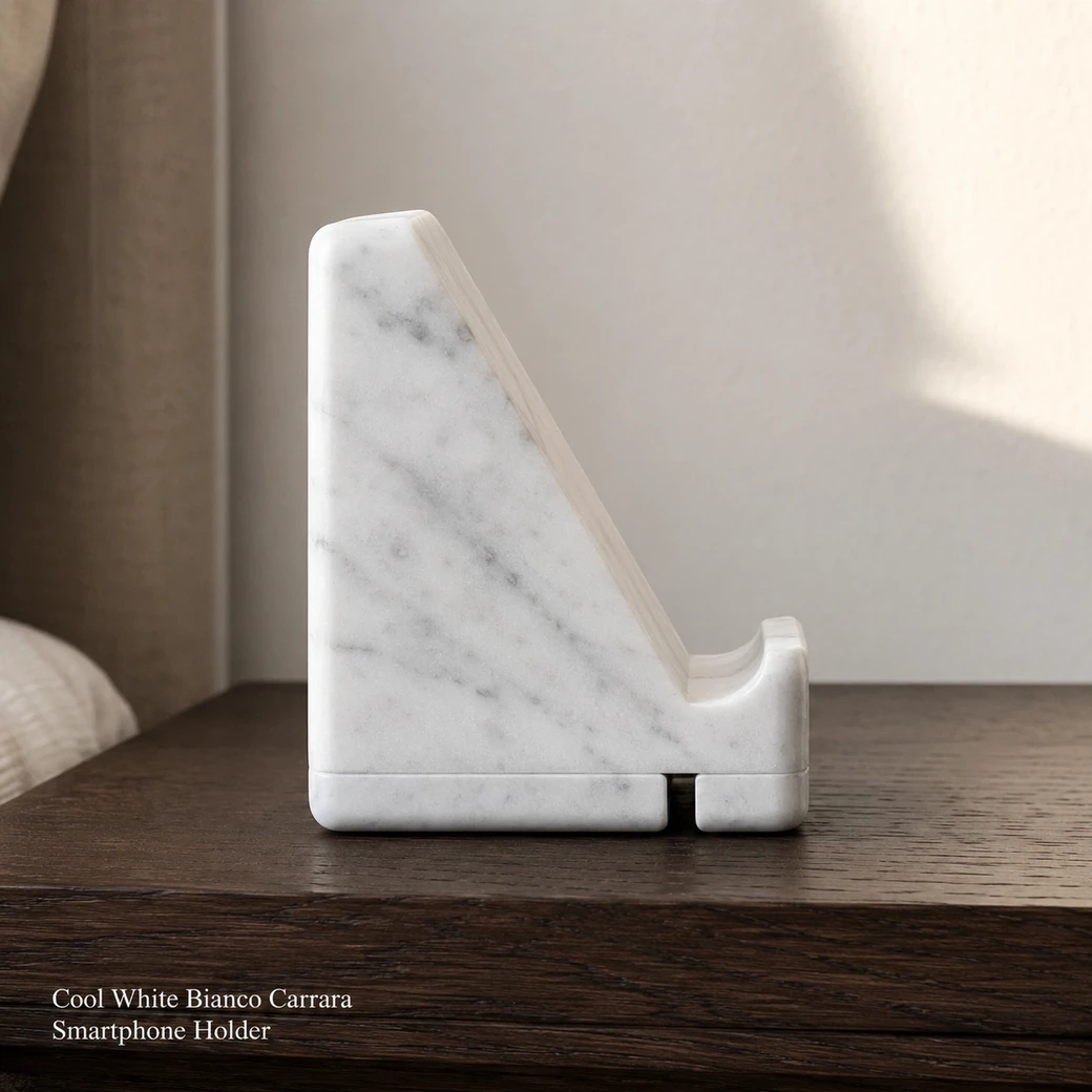 Cool white Bianco Carrara phone holder on dark oak, side profile showing tilt, ledge and charging slot