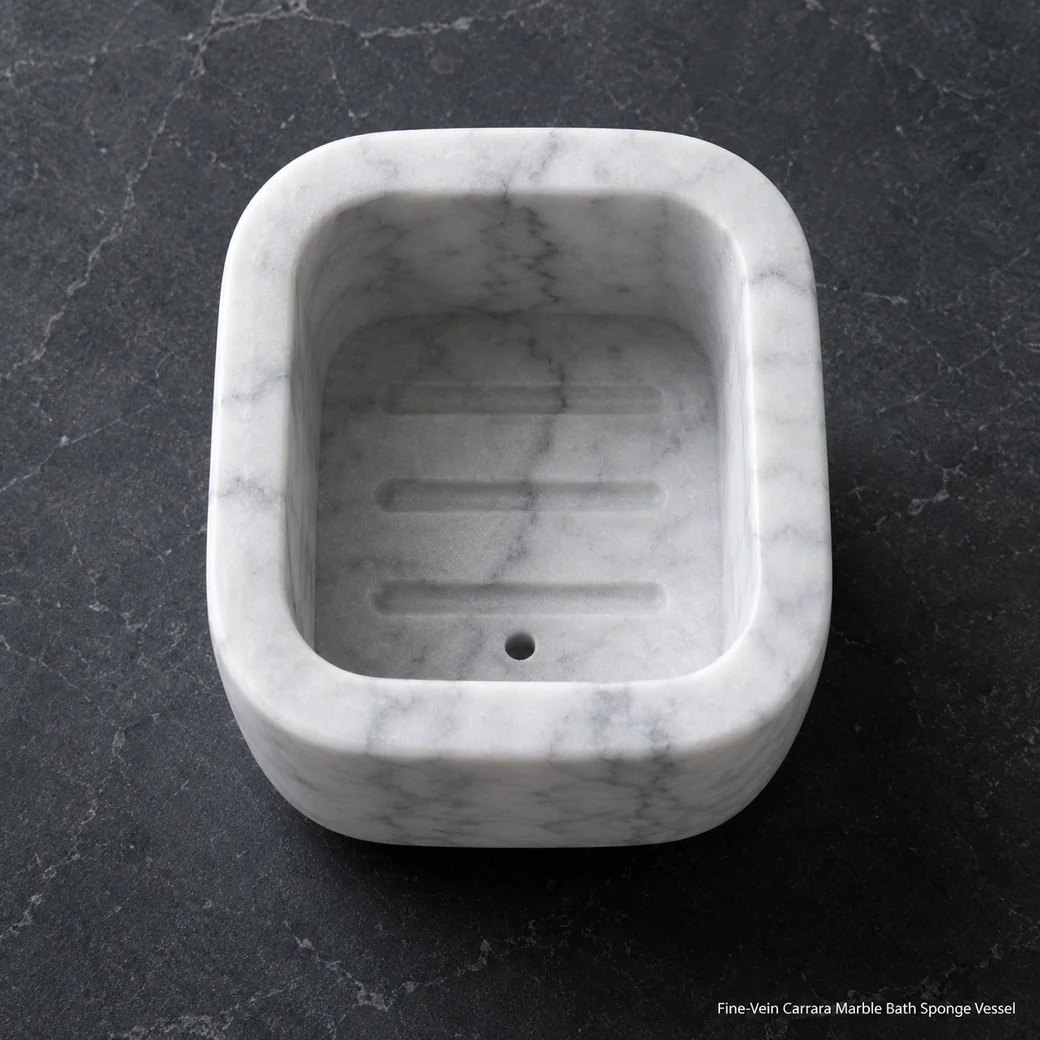 Frost white Carrara sponge vessel on dark slate, overhead view showing inner grooves and fine grey mineral detail.