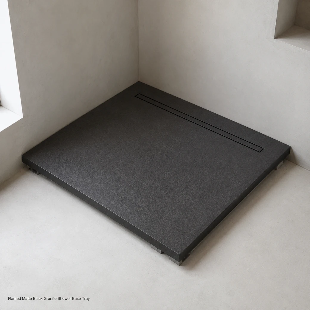 Matte black granite shower base in white wet room, high corner view showing flamed texture, drain and 3 cm edge.