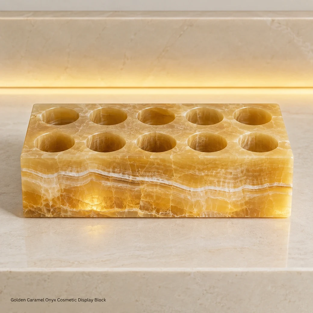 Caramel onyx lipstick block on ivory vanity, high front view showing empty wells and glowing mineral layers.