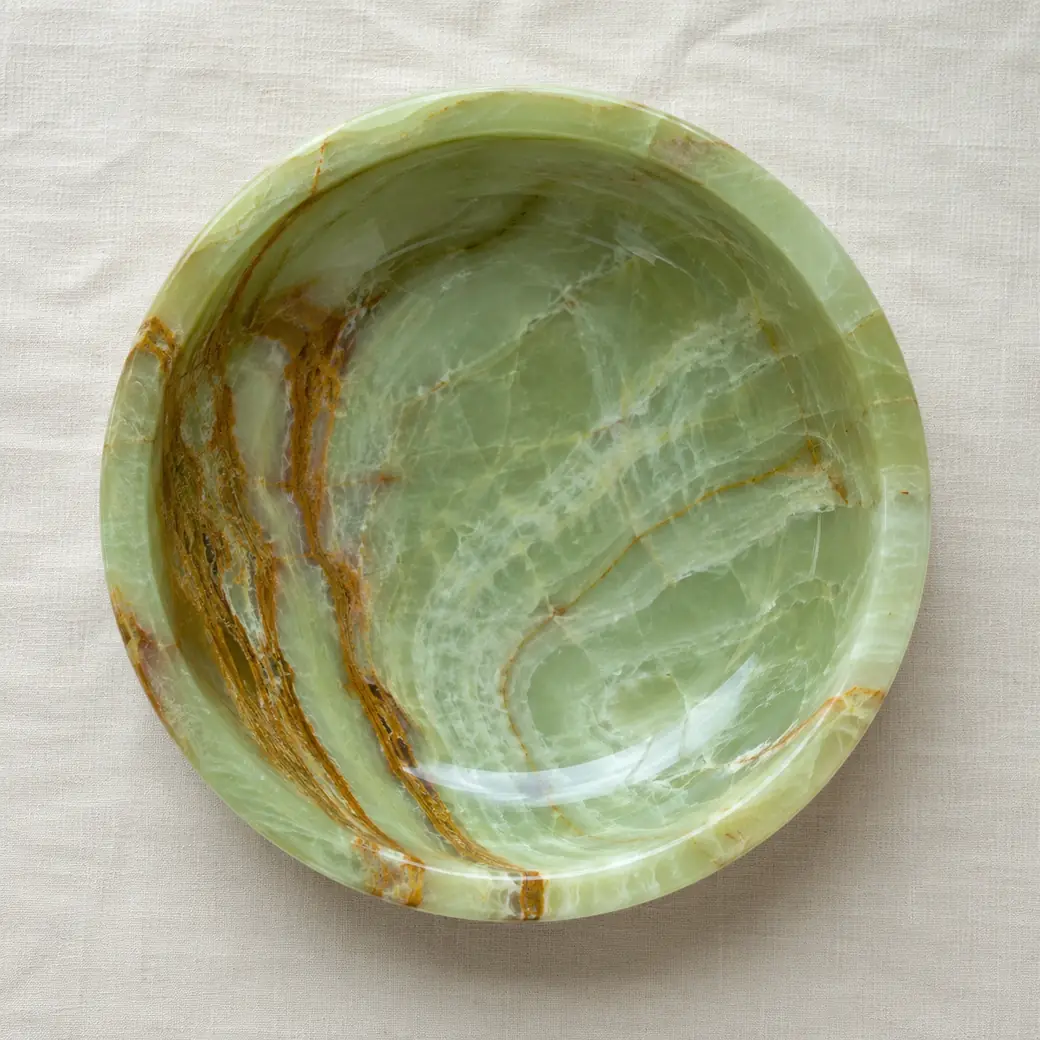 Overhead Green Onyx bowl on ivory linen with jade, rust-brown bands and polished translucent depth.
