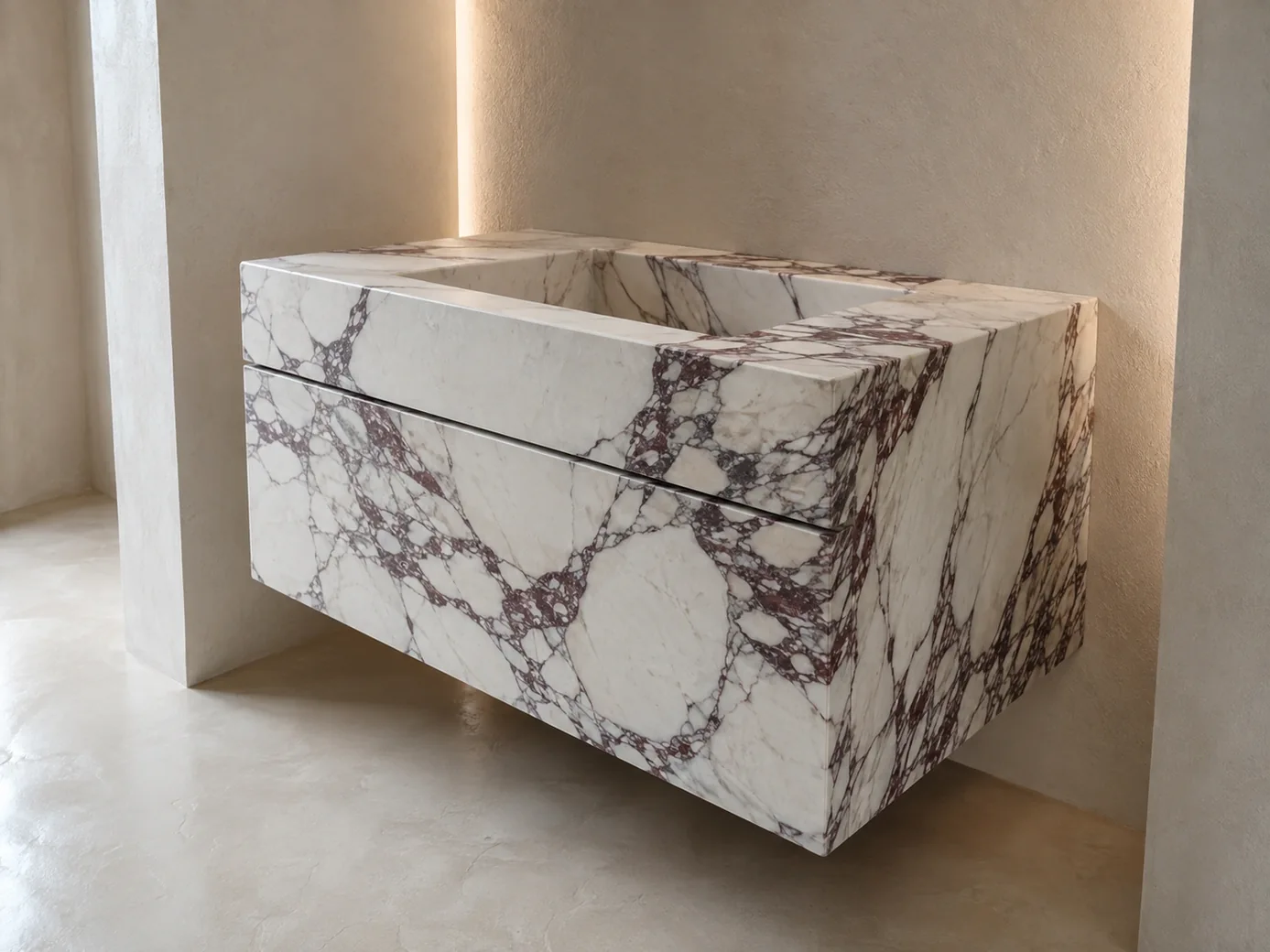 Calacatta Viola floating vanity shown from a low side angle in an ivory microcement alcove