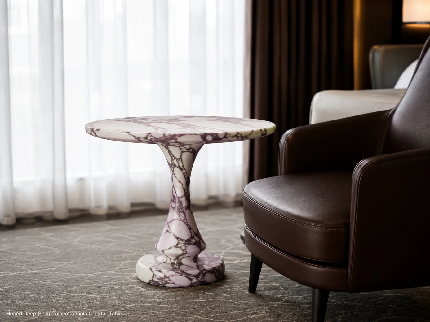 Honed deep-plum Calacatta Viola cocktail table shown in profile beside a dark leather lounge chair