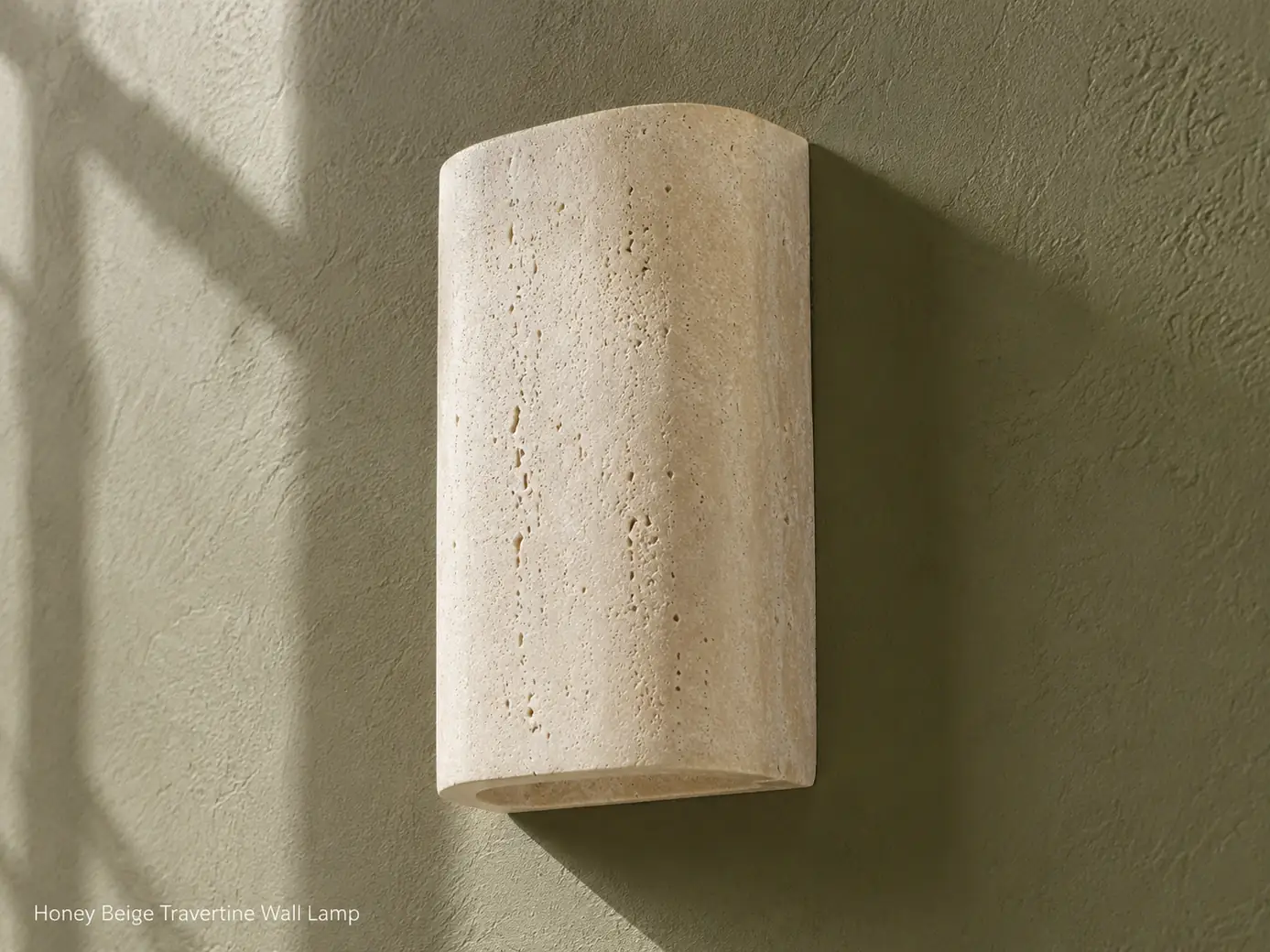 Unlit honey-beige travertine wall lamp shown from the side on a deep olive plaster wall