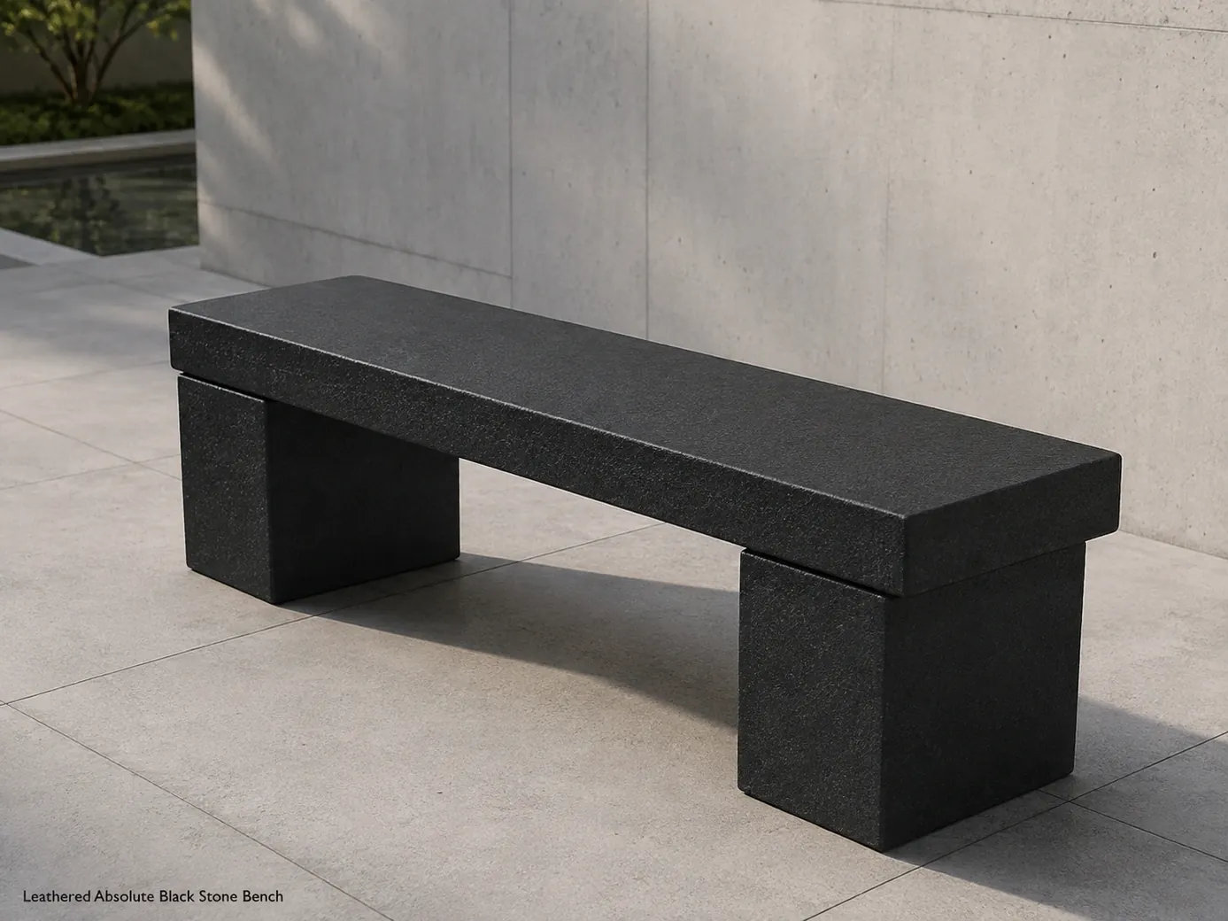 Leathered black granite bench viewed from the rear in a pale concrete courtyard under morning light
