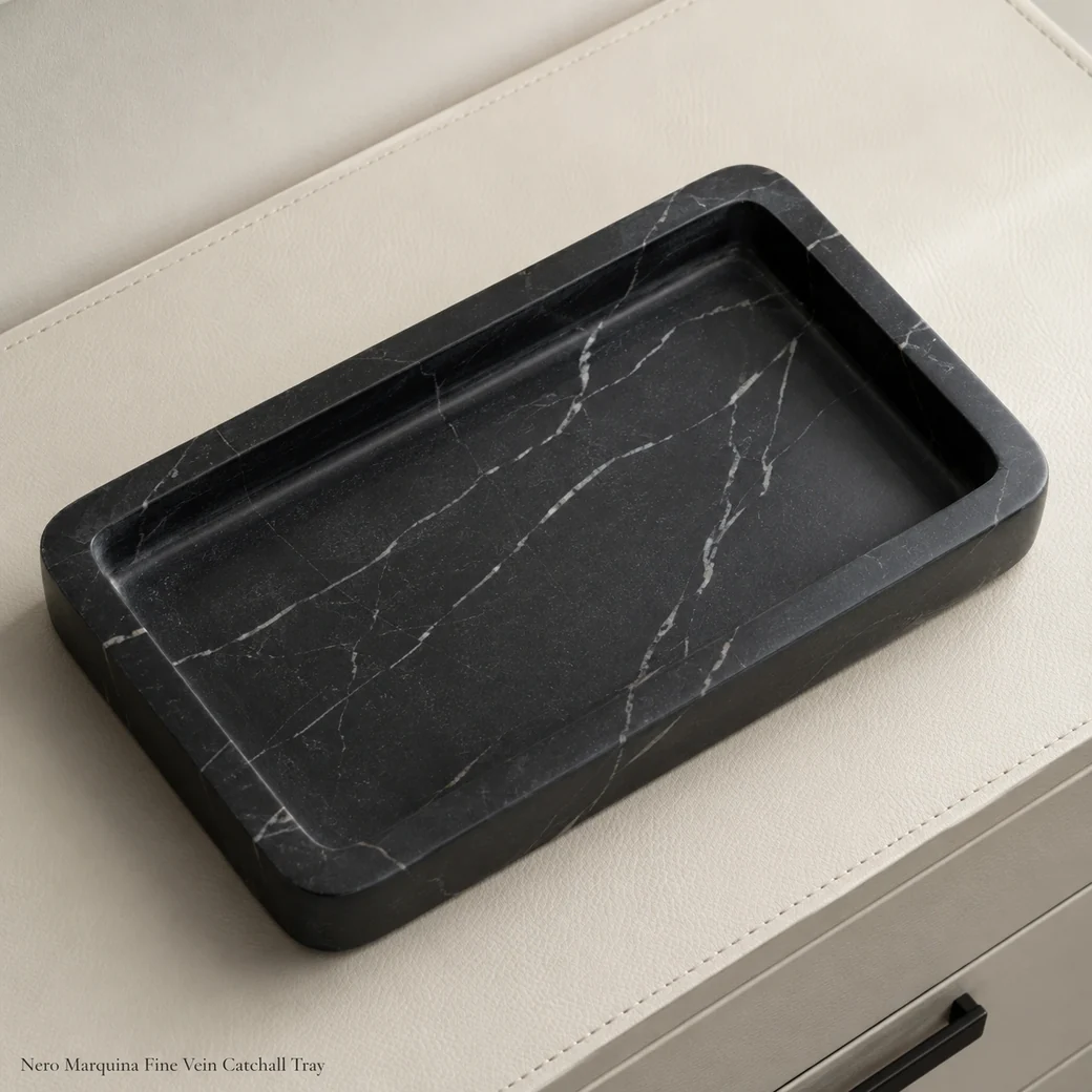 Nero Marquina catchall tray on cream leather console, overhead diagonal view with fine veins and soft Brosso texture.