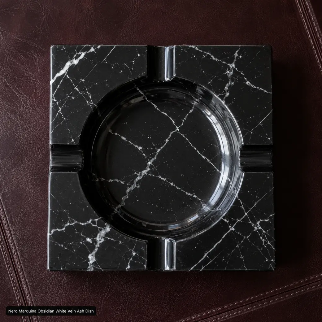Top-down Nero Marquina ashtray on burgundy leather, showing four rests, carved bowl and dramatic white vein network.