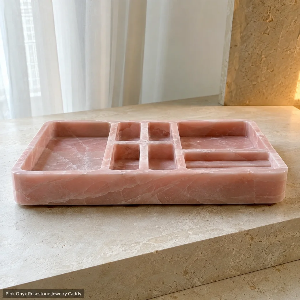 Low side view of rose Pink Onyx jewelry caddy on limestone, revealing carved recess depths and satin-honed compartment walls.