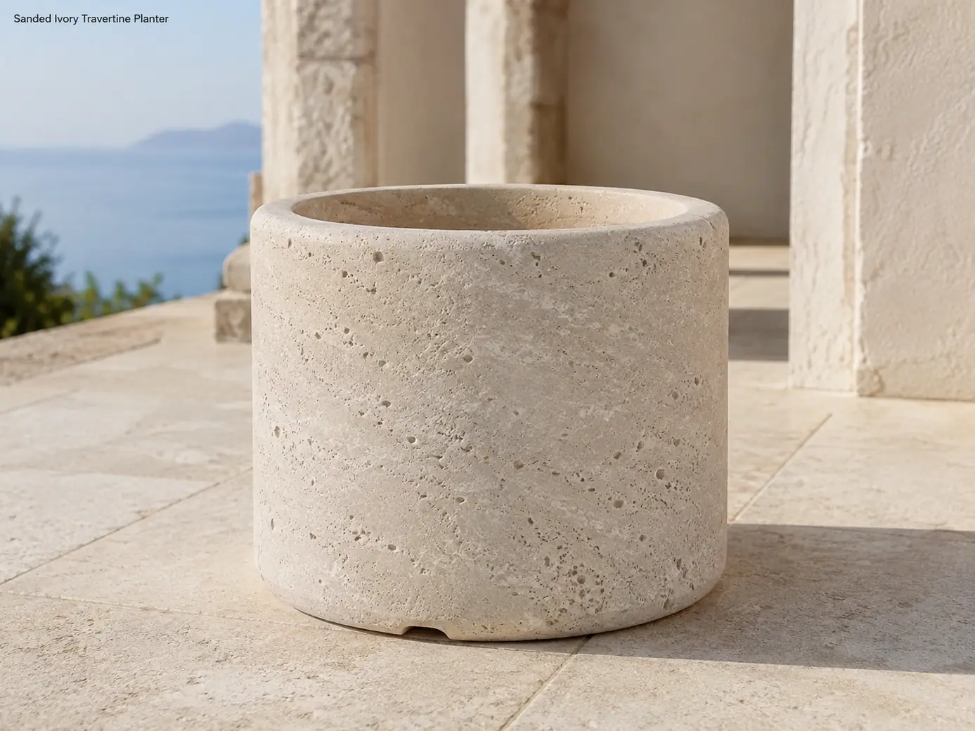 Empty ivory travertine planter photographed at ground level on a Mediterranean limestone terrace