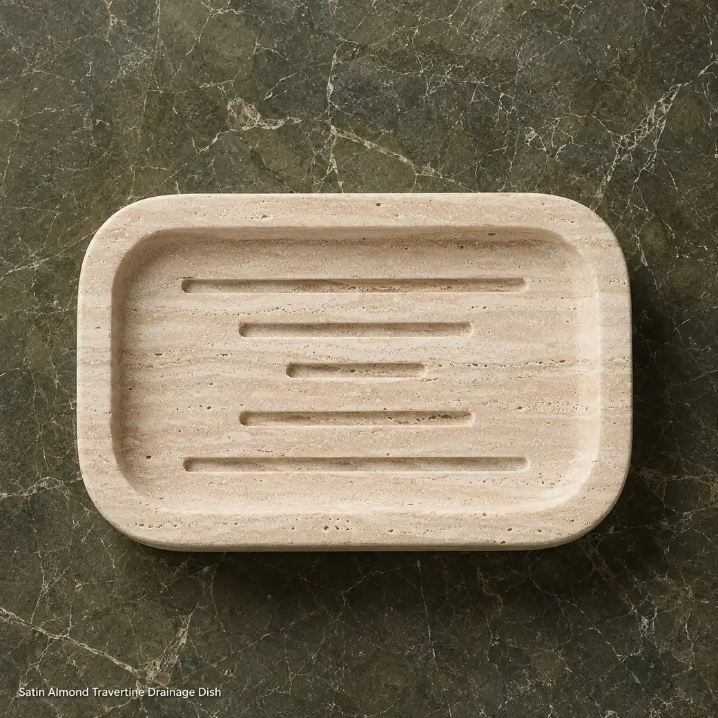 Overhead almond travertine soap dish on dark olive stone with satin finish and precise drainage grooves.