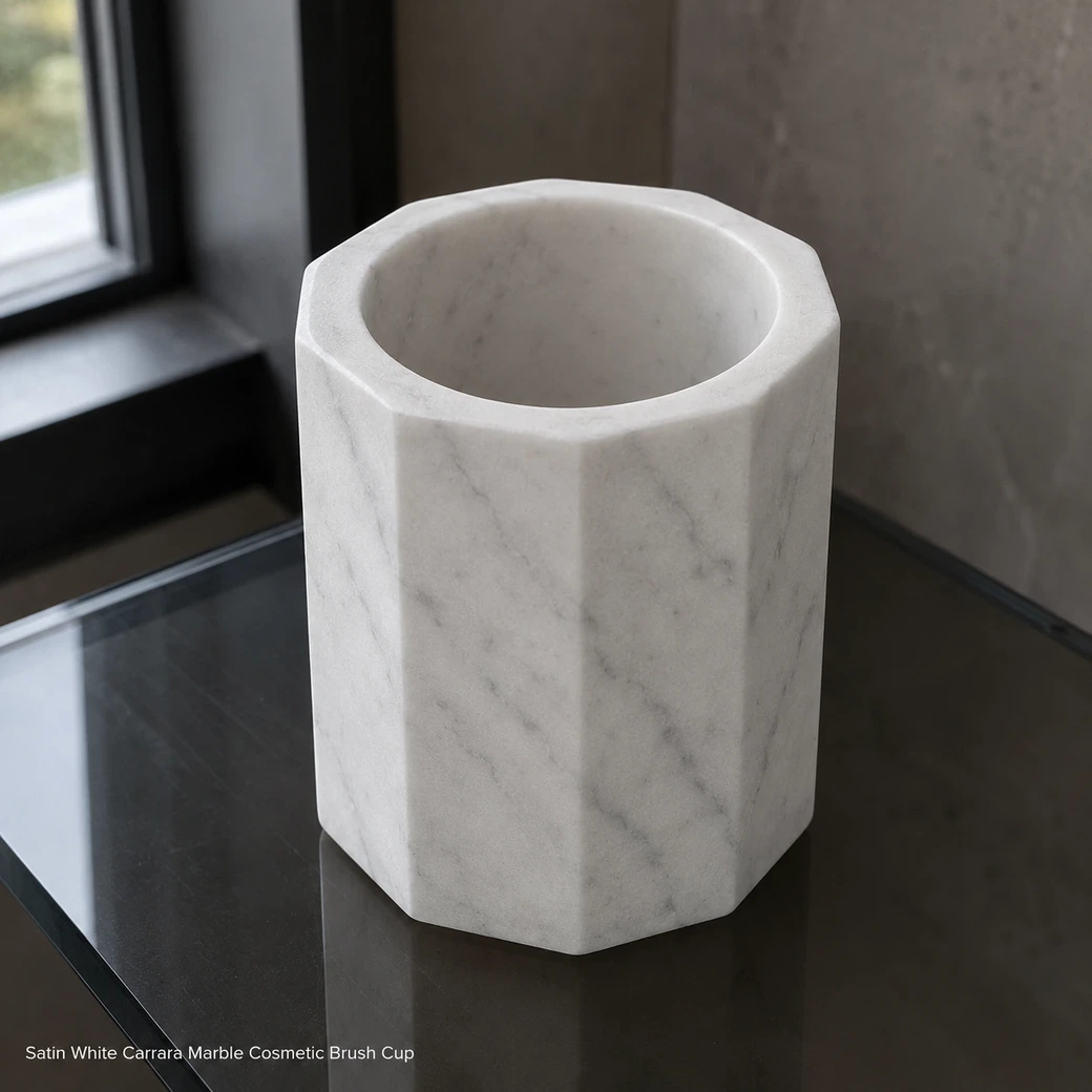 Satin white Carrara cosmetic brush cup on smoked glass vanity, high rear view showing faceted form and grey veins.