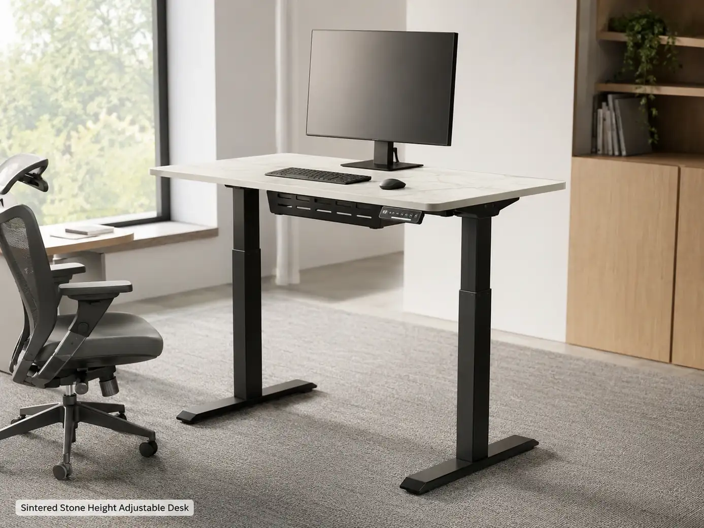 Warm white sintered stone height-adjustable desk in standing position with monitor, keyboard and cable tray.