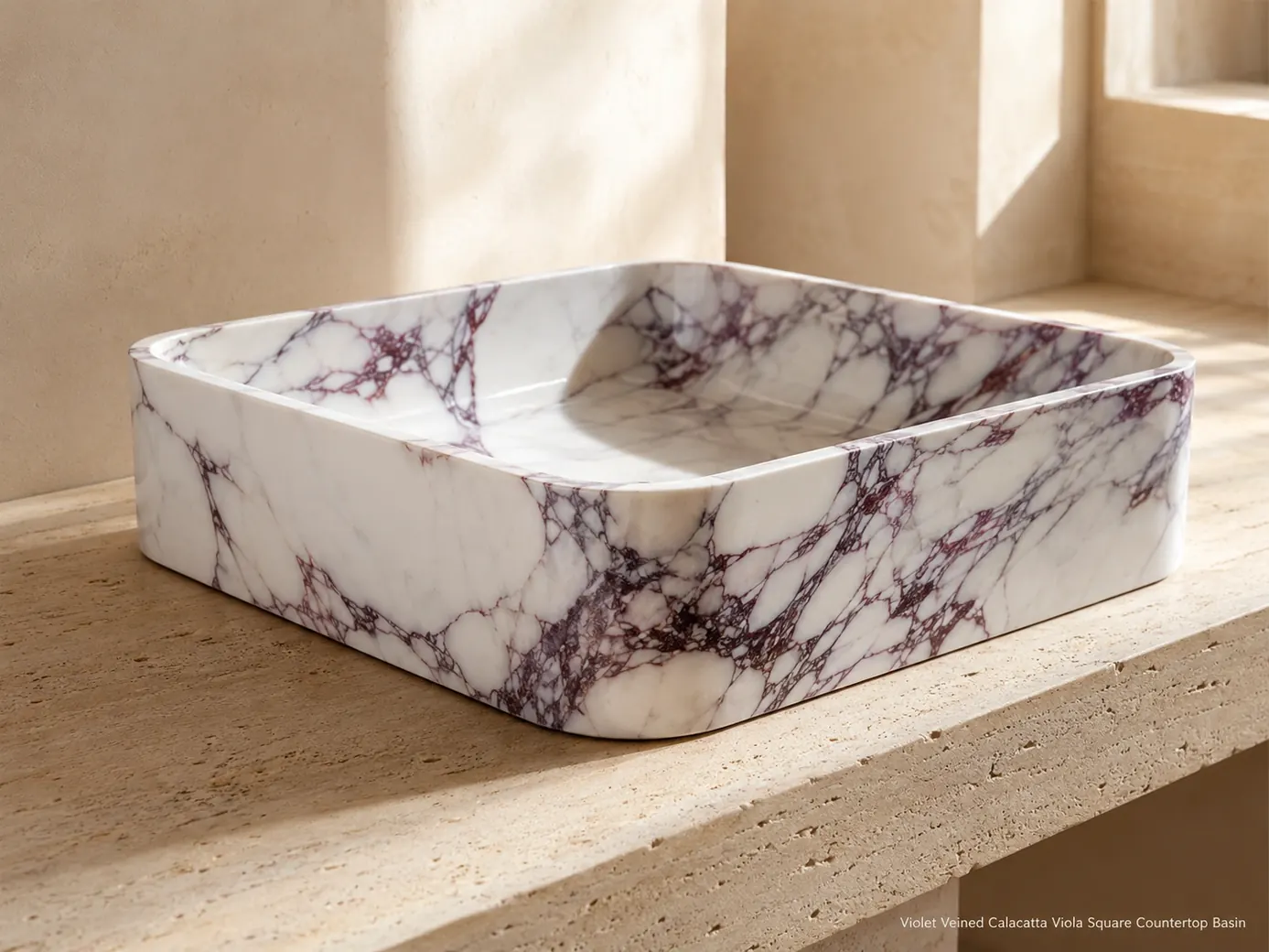 Low rear view of polished Calacatta Viola square basin on pale travertine, glowing white with violet veins.