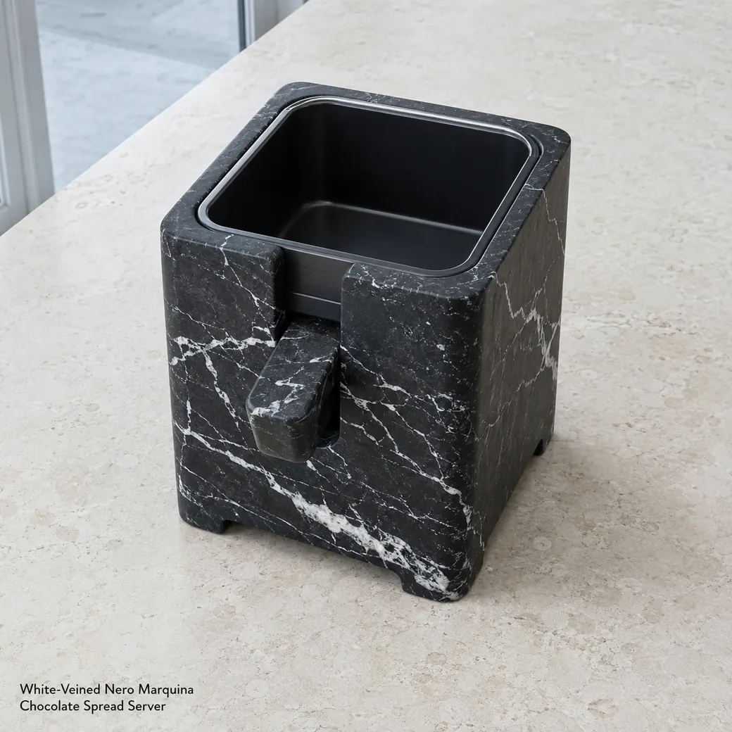 Nero Marquina spread dispenser on pale limestone, high front view showing white veins and front control lever.