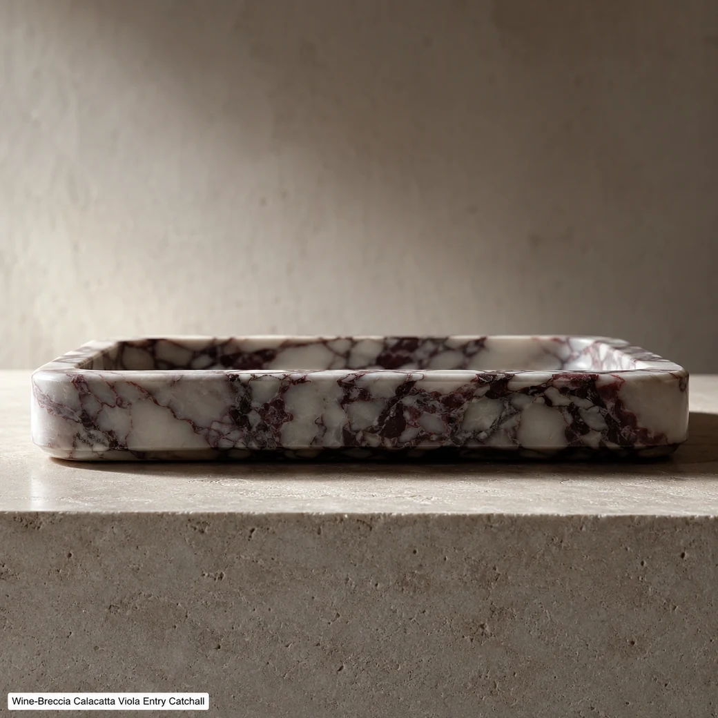 Low end-on Calacatta Viola key tray on limestone with burgundy-grey veins and brushed satin edge.